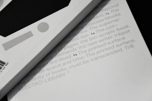 Close-up macro shot of white printed books with typography and graphic shapes against a dark background