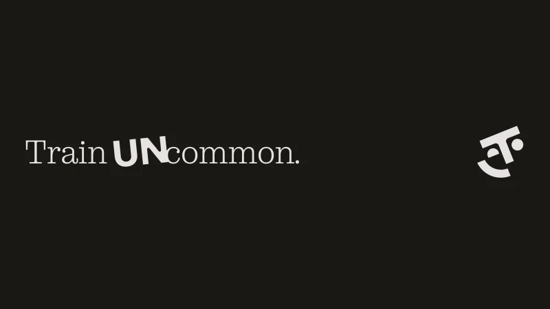 Promotional image with the text 'Train UNcommon' in a sans-serif typeface and a stylized geometric logo on a dark background.