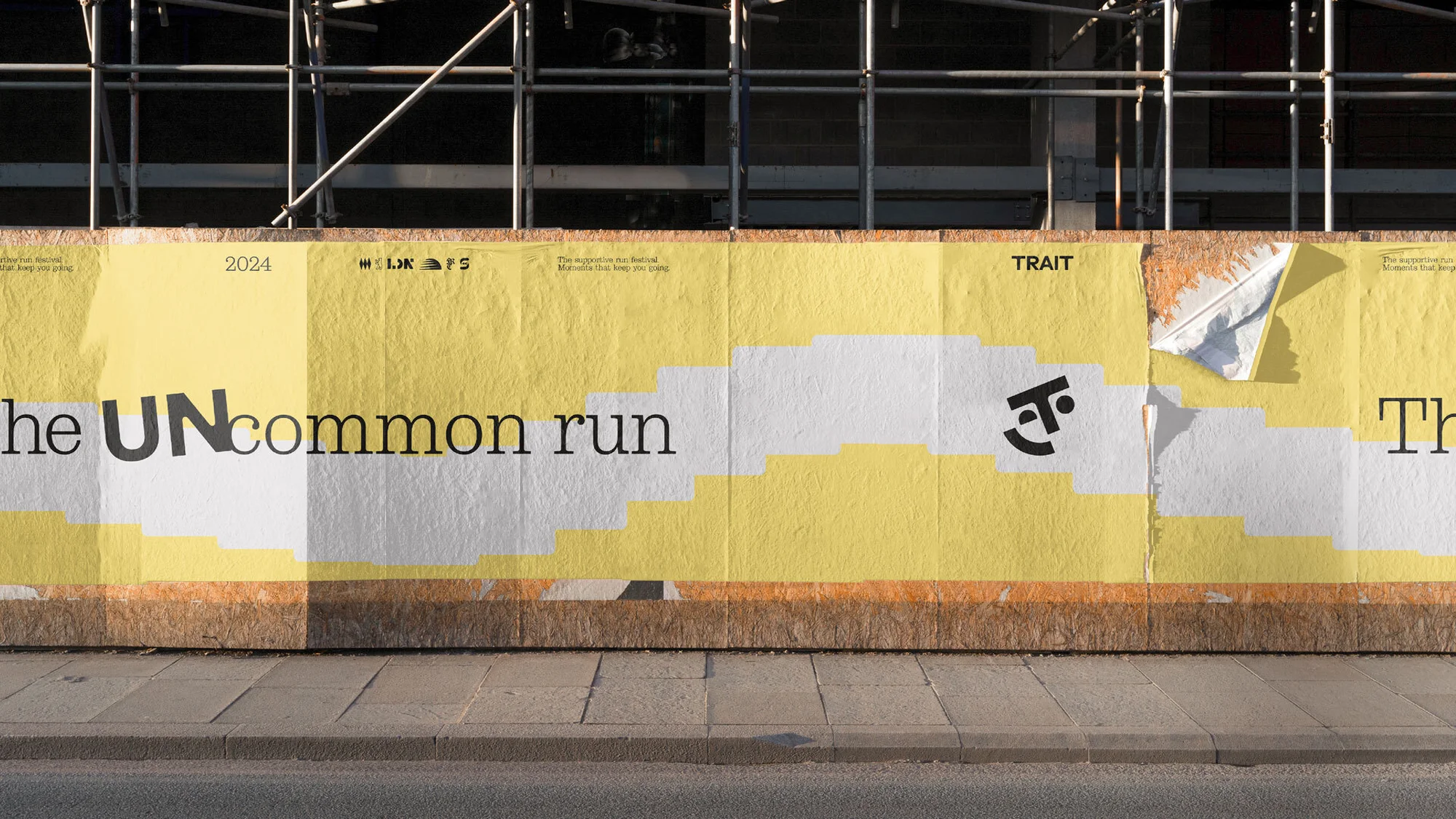 Outdoor advertising billboard featuring 'The Uncommon Run' event with a playful logo, set against a city sidewalk and scaffolding.