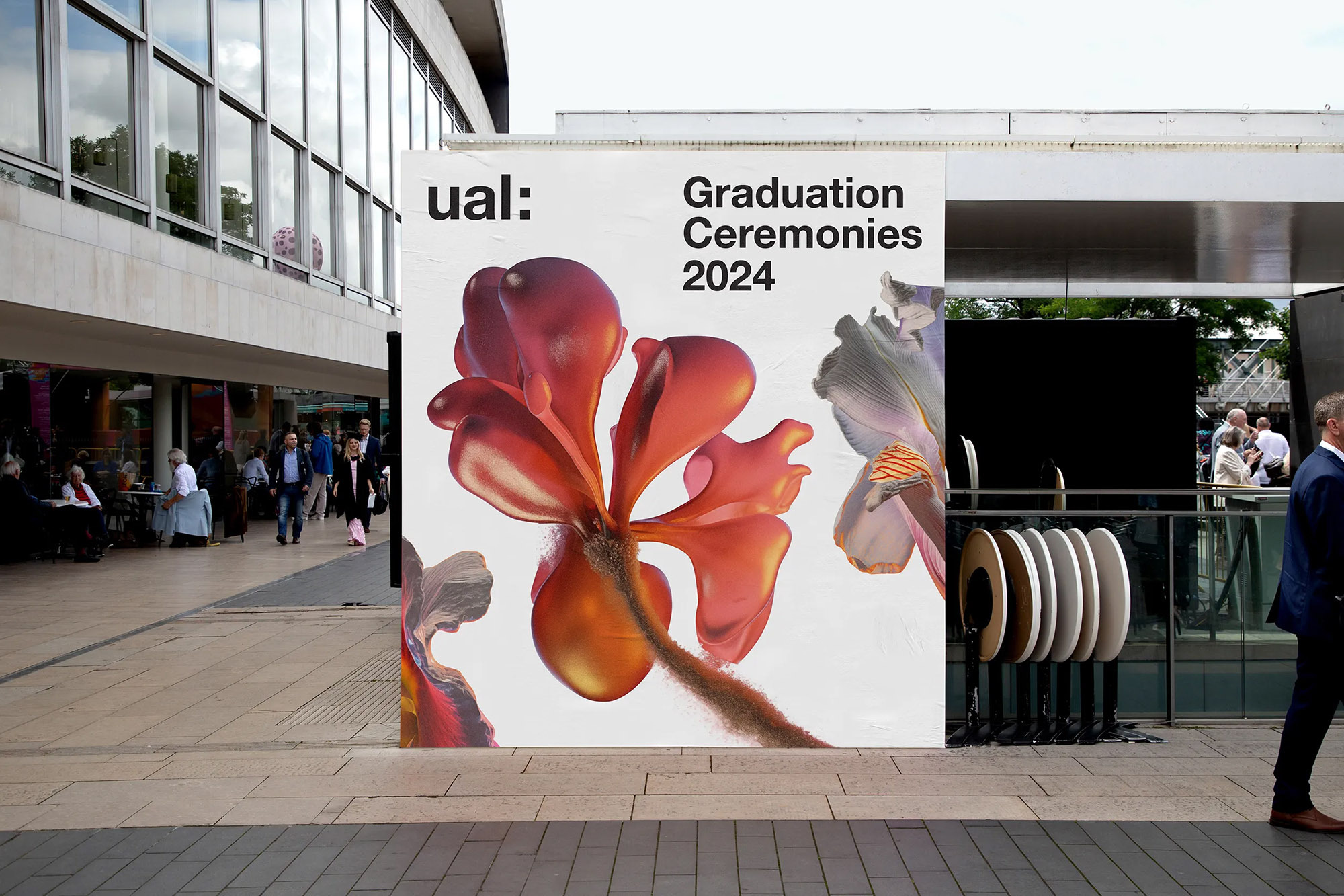 University Arts London (UAL) graduation ceremony advertising displays large floral visuals on a city building, outdoor urban scene.