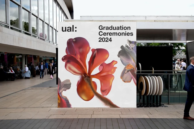 University Arts London (UAL) graduation ceremony advertising displays large floral visuals on a city building, outdoor urban scene.