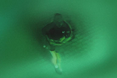 Motion blurred figure running through a green tinted night vision tunnel for Running Order brand identity