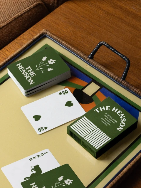 Close-up of a deck of green and white playing cards and their box on a decorative tray with a colorful geometric design.