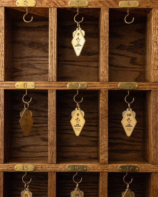 Wooden key rack with numbered brass hooks holding diamond-shaped key fobs at a hotel or inn, showcasing a vintage aesthetic.