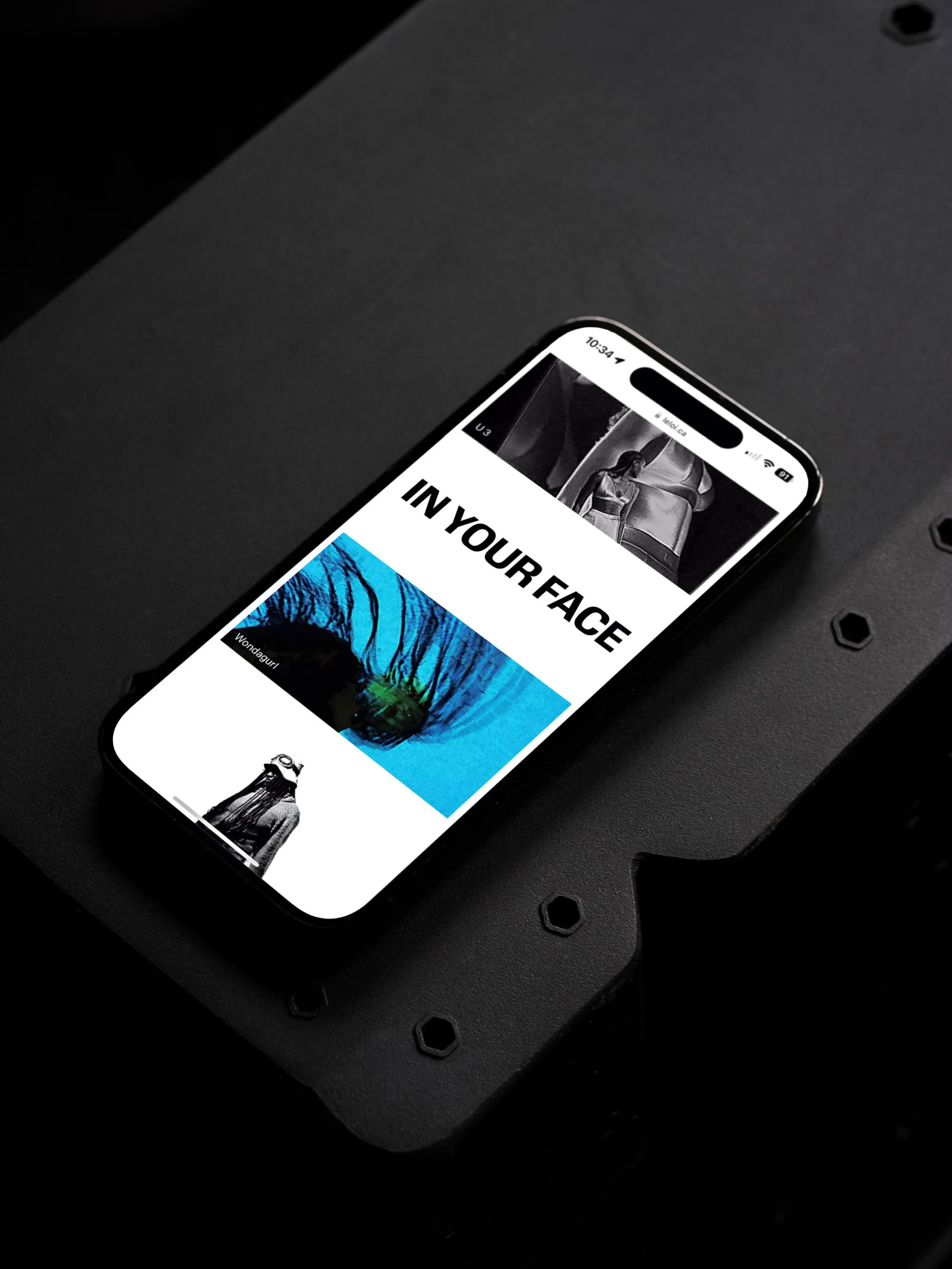 Smartphone displaying an editorial layout with text overlay and abstract images, resting on a textured black surface in a studio setting.