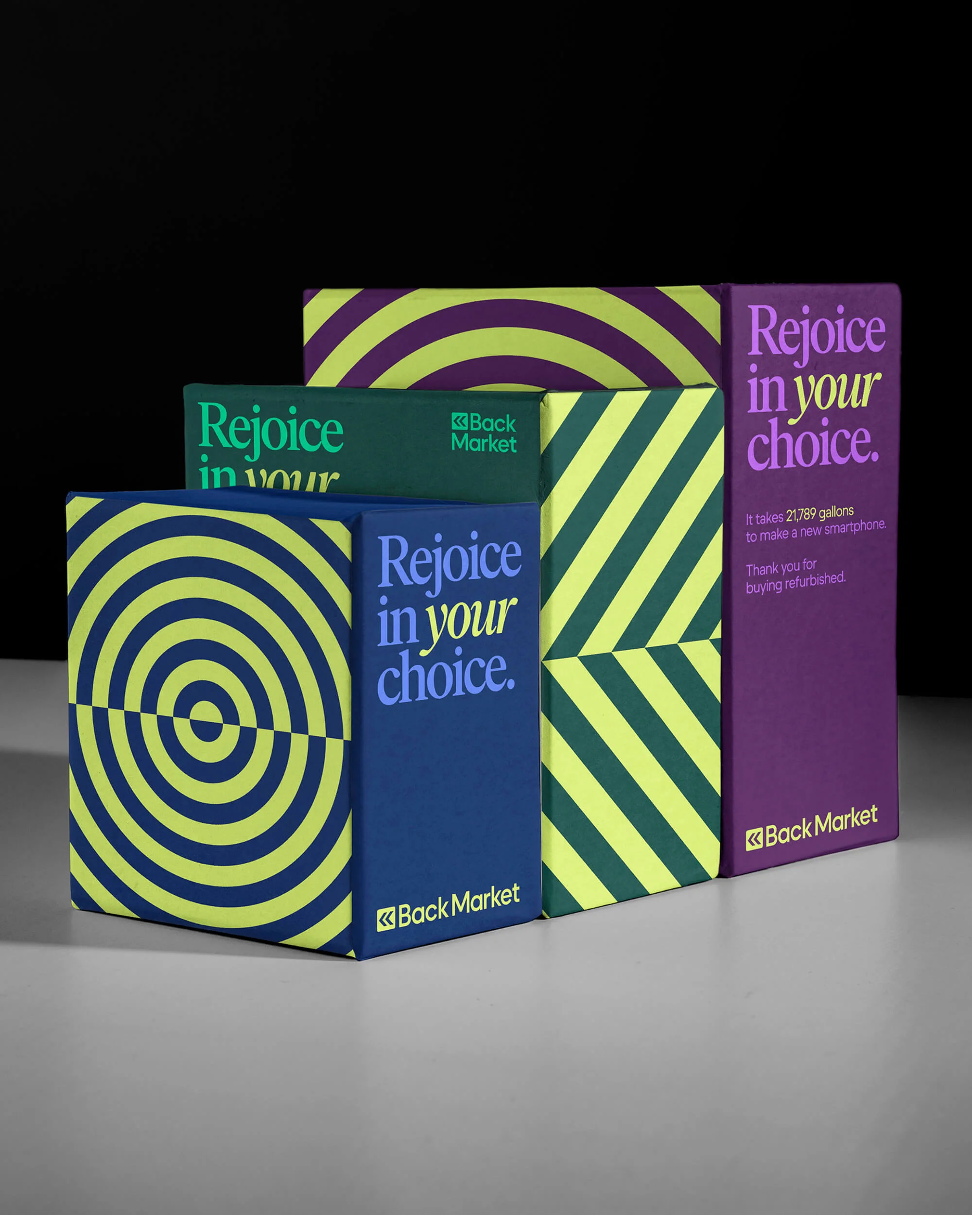 Back Market branded packaging in purple, green, and blue, arranged in a staggered row on a grey surface against a black background.