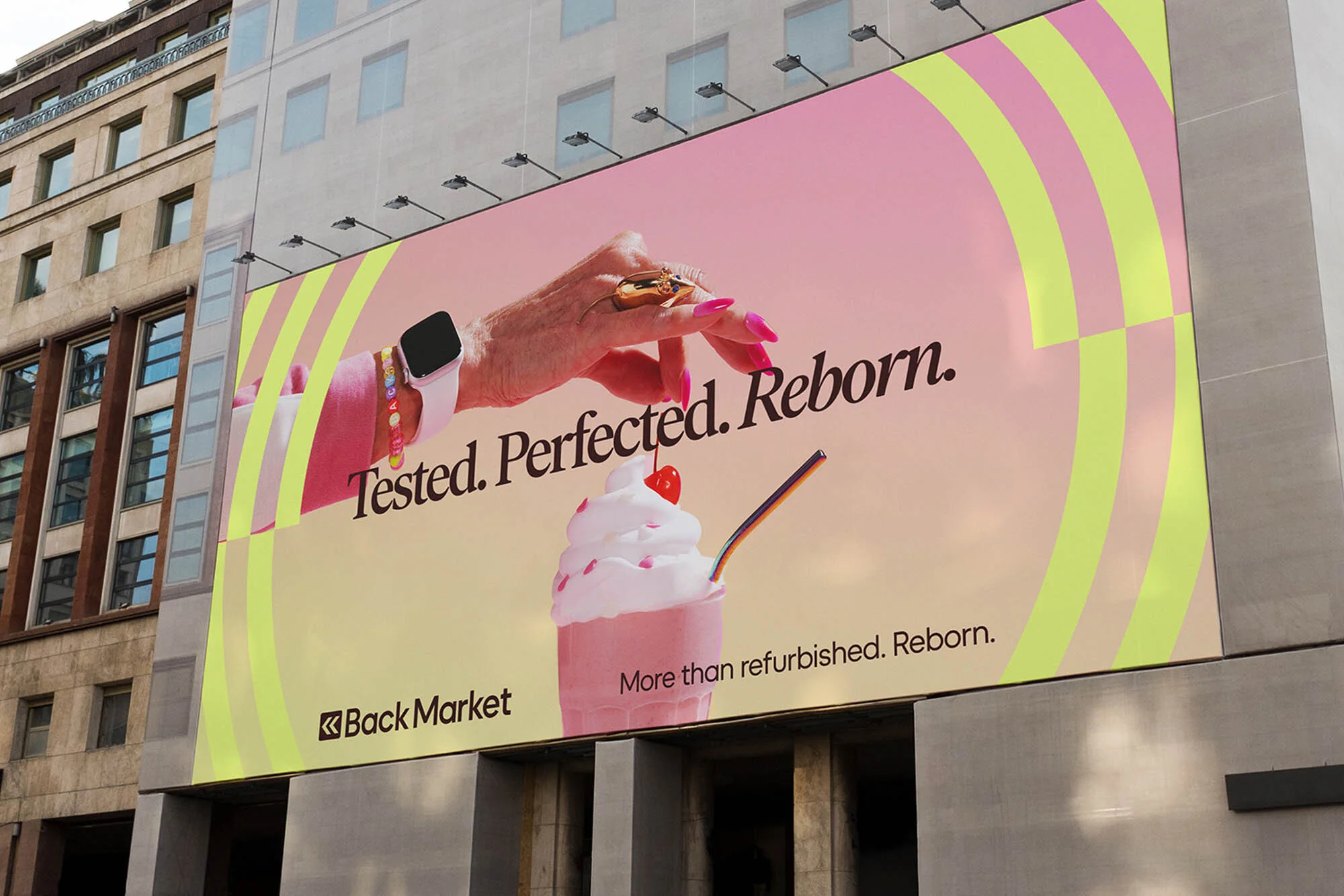 Billboard ad featuring a hand with jewelry, a smartwatch, and a cherry milkshake with the Back Market logo on a building.