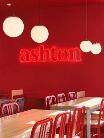 Restaurant interior with red walls, wooden tables, and hanging spherical lights under a bright, inviting light.