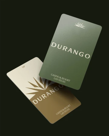 Two cards displaying 'Durango Casino & Resort Las Vegas', one green and one tan, are angled against a dark background in a studio shot.