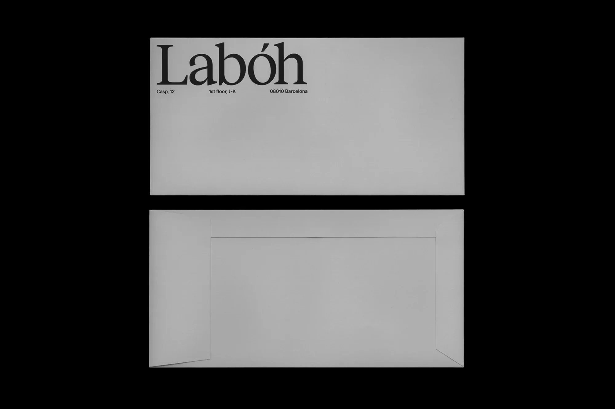 Two light gray envelopes are displayed against a black background, with black sans-serif typeface. The top envelope is printed.