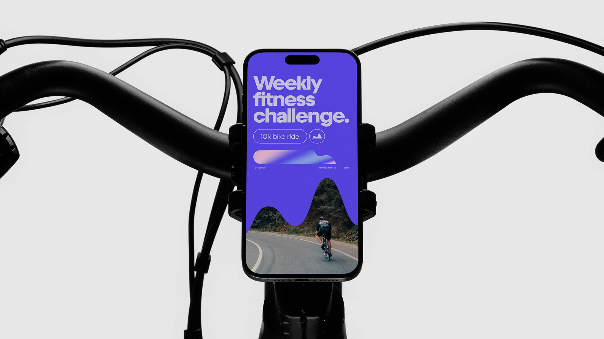 Mobile phone displaying a fitness challenge app mounted to a bicycle handlebar, set against a clean, bright background.