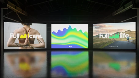 Three large digital screens display brand identity graphics for Spectrum.Life inside a dark warehouse interior.