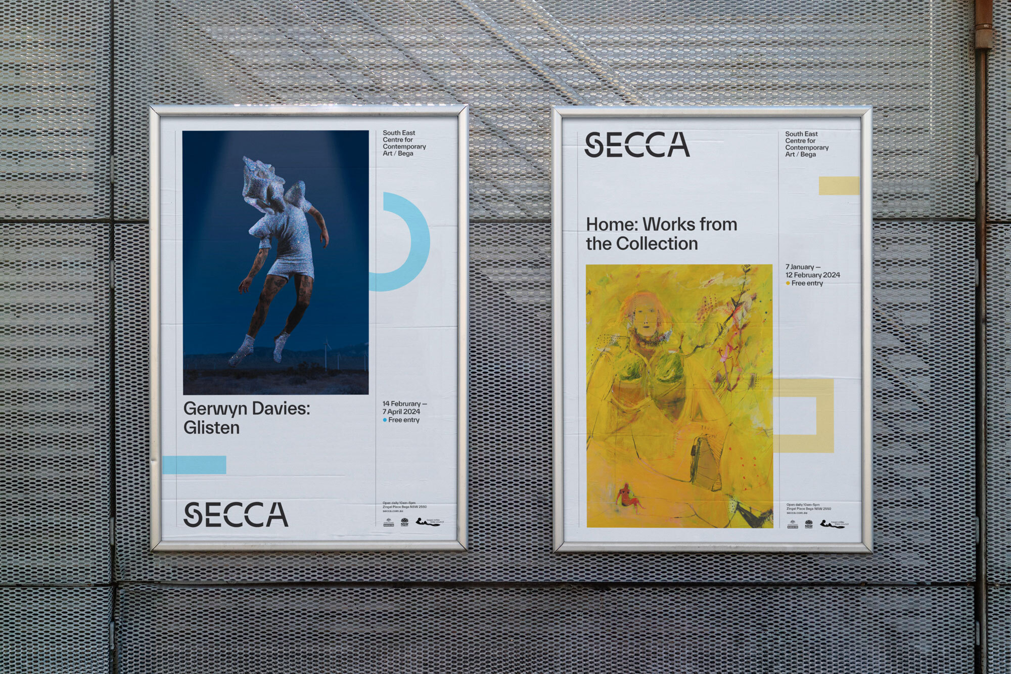 Two framed art exhibition posters on a grey wall, featuring artwork and event information, promoting SECCA, a contemporary art space.