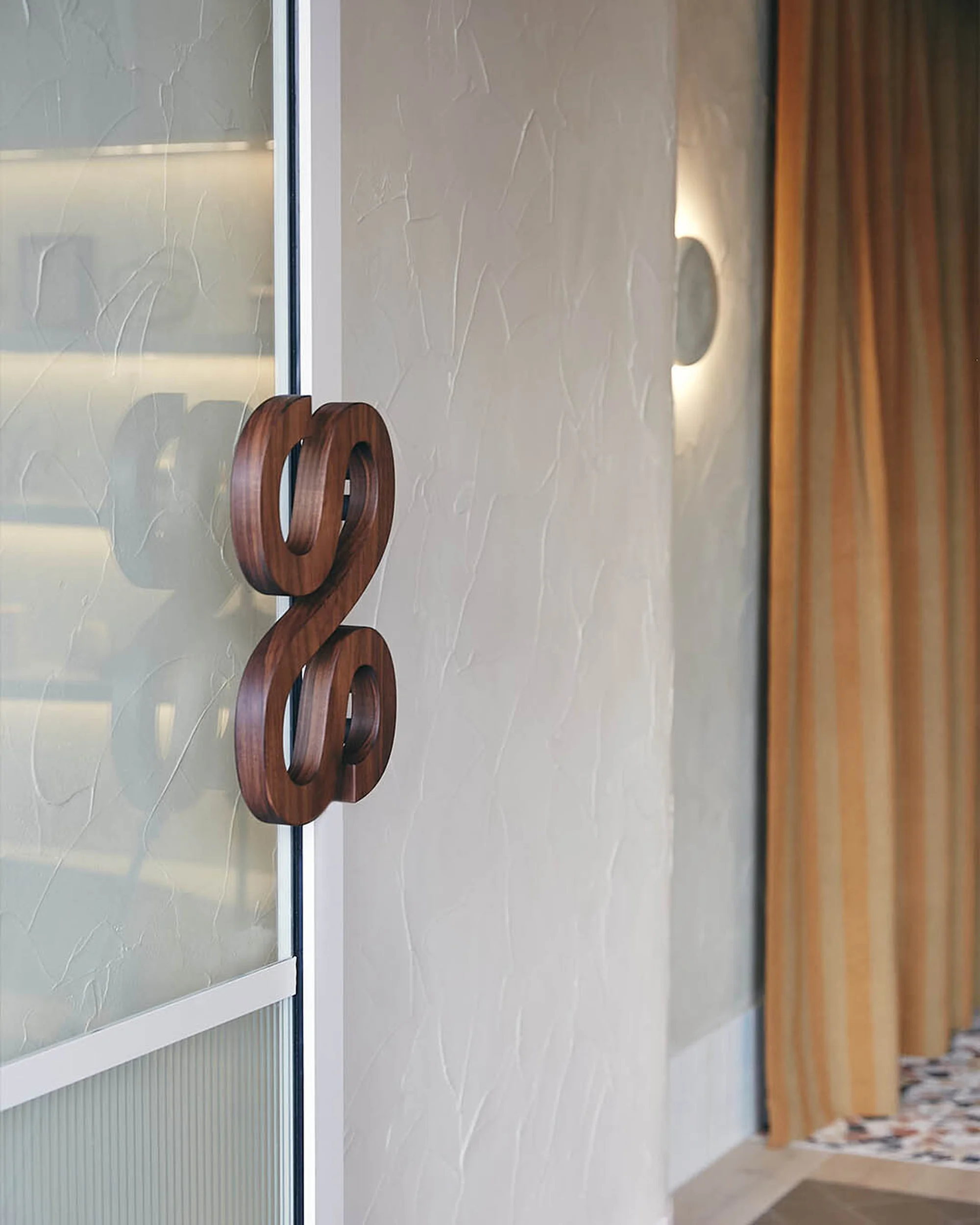 Door with unique wooden handle. Modern design features a white frame, beige walls, stylish interior, and soft, diffused lighting.