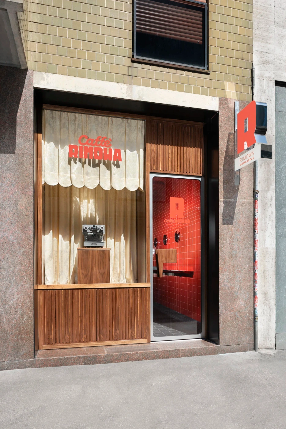 Exterior storefront of Caffe Rimowa with wood paneling, cream curtains, and a bright red interior visible through the glass door.
