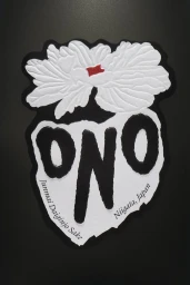 Embossed white flower graphic over bold black typography spelling ONO against a dark background for Sake Ono brand identity.