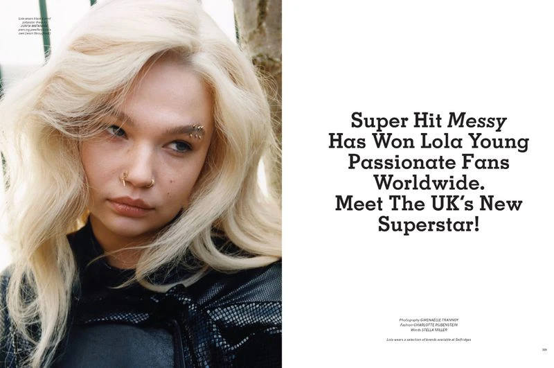 Close-up portrait of a blonde woman with an eyebrow piercing and nose ring, wearing a black leather jacket, alongside magazine text.