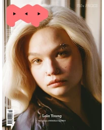Close-up portrait of singer Lola Young with blonde hair, facial piercings, and dark jacket for Pop Magazine editorial.