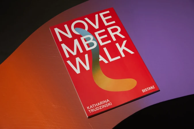 Art book 'November Walk' by Katharina Trudzinski featuring a vibrant red cover with abstract design on a multicolored surface.
