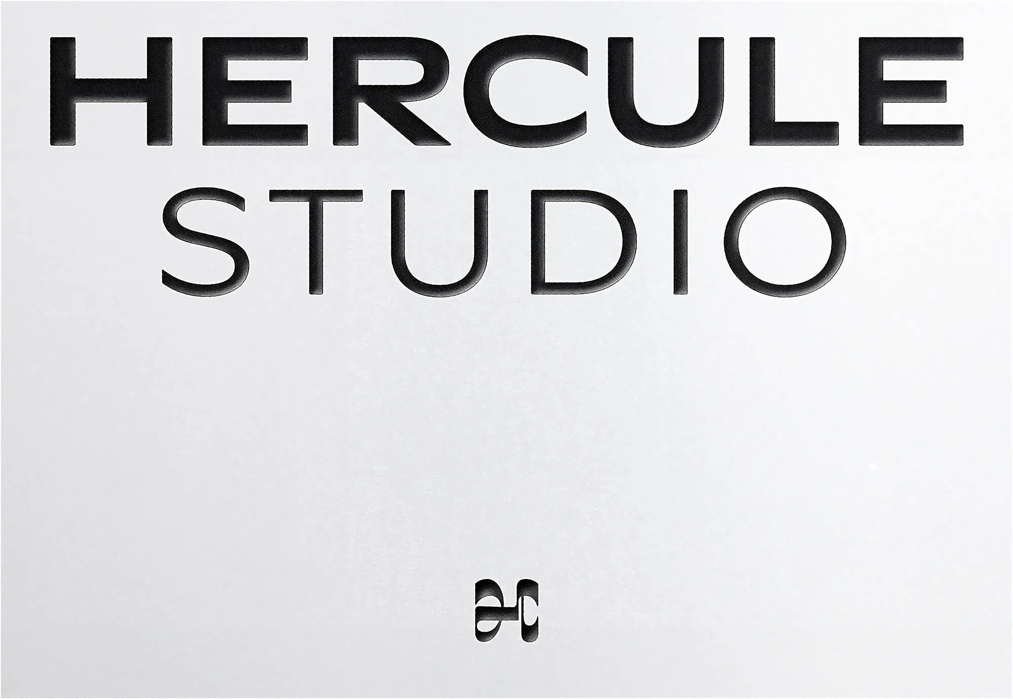 Embossed black typography reading Hercule Studio on a clean white paper background with a small monogram mark.