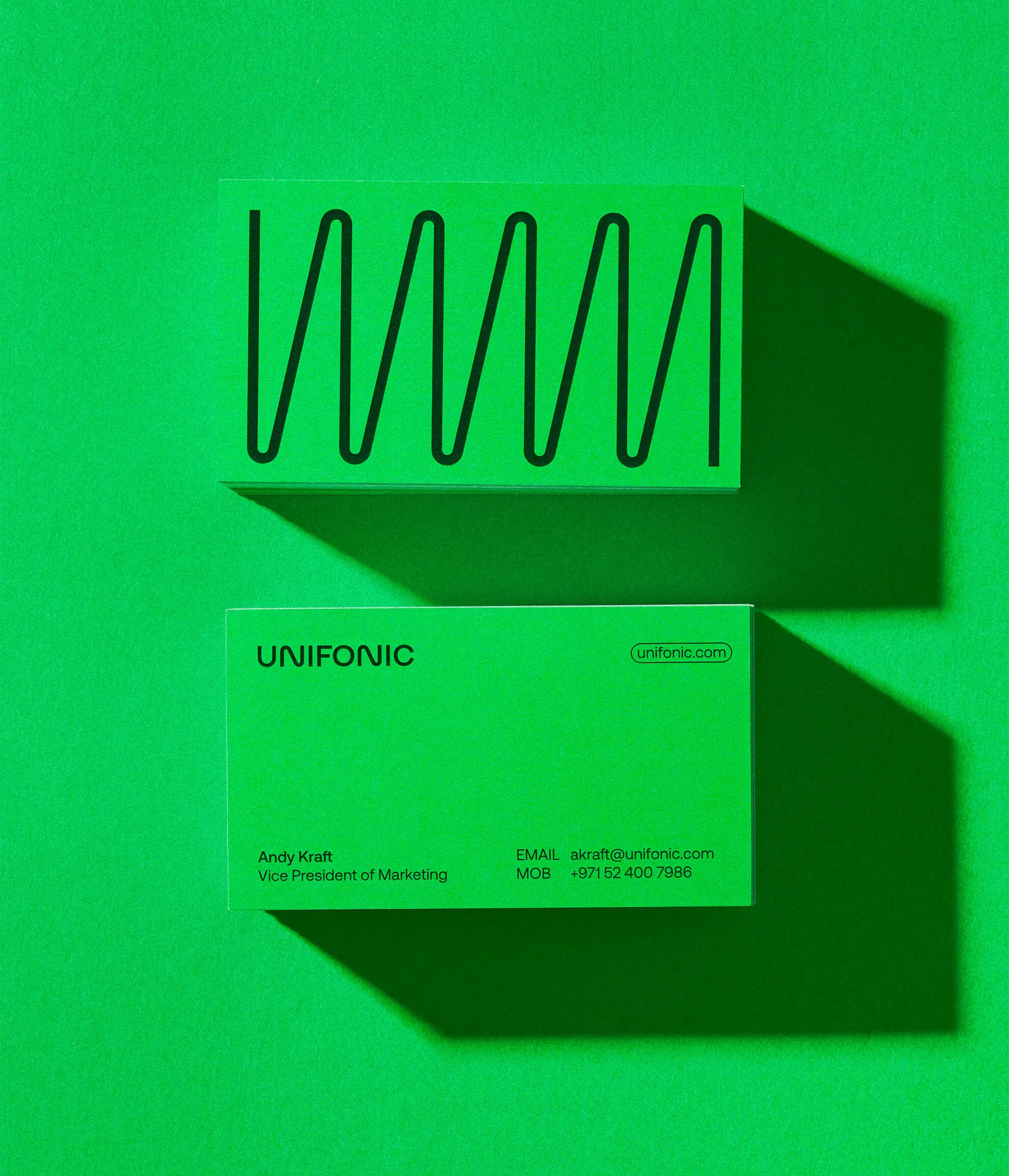 Two bright green Unifonic business cards displaying minimalist typography and a geometric wave line on a solid green background