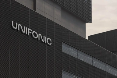 Unifonic brand identity displayed as a dimensional silver logo on a dark gray louvered corporate building exterior under an overcast sky.