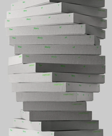A towering stack of grey and white textured books featuring green typography against a plain light background