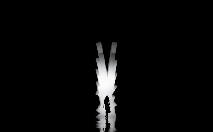 Silhouette of woman walking through a bright light against a dark background. Person in motion, fashion or conceptual photography.
