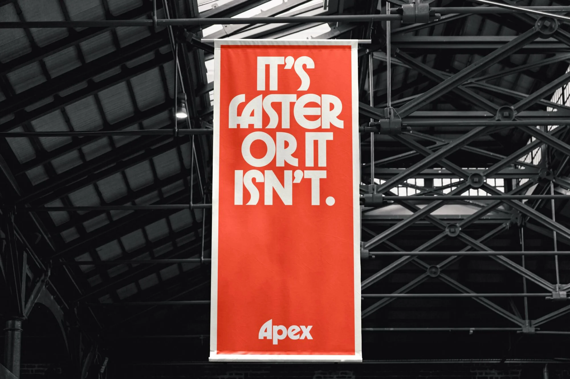 Red and white Apex banner hanging indoors, with the text: 'It's faster or it isn't.' Black industrial ceiling in the background.
