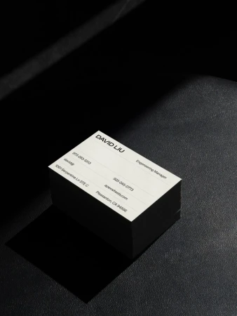 Stack of business cards for David Liu, Engineering Manager, with contact details, photographed in a studio with dramatic directional lighting.