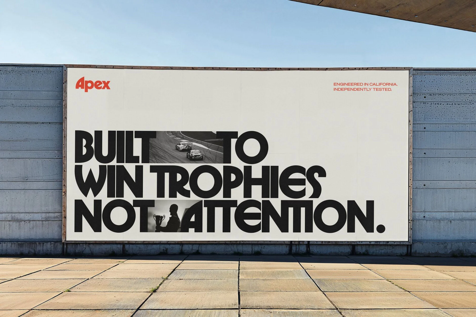 Outdoor billboard featuring race cars and a trophy, stating, 'Built to Win Trophies Not Attention,' set against a concrete wall.