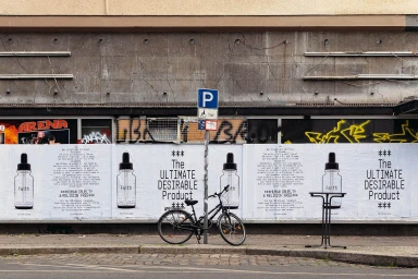 Bicycle parked on a city street against a pasted poster wall displaying product advertisements for Amateur Rocks.