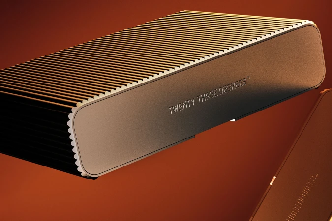 Close-up of an elongated bronze rectangular device with ridged top, featuring the text 'TWENTY THREE DEGREES' against an umber background.
