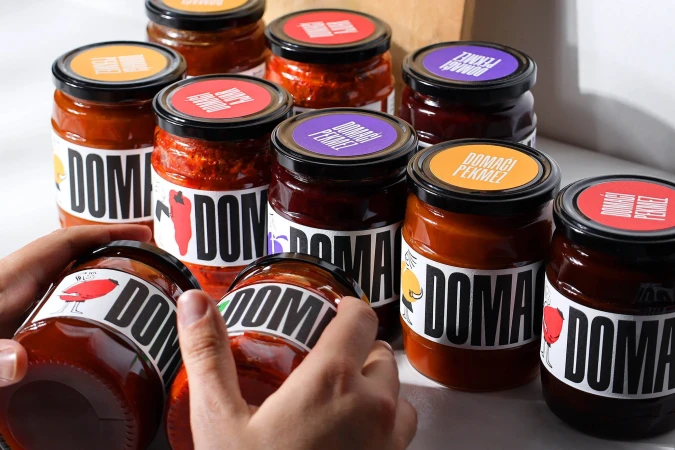 Close-up of hands holding glass jars with custom white and black labels and colourful lids for Kopex Brand Identity.
