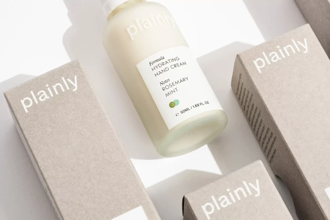 Cosmetic product display featuring hand cream and packaging, set against a clean white backdrop, highlighting minimalist design.