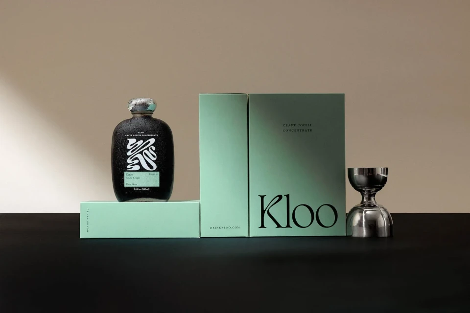 Craft coffee concentrate displayed with a sleek bottle, branded packaging, and a silver jigger against a neutral background.