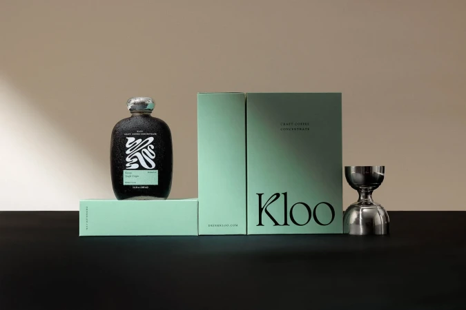 Craft coffee concentrate displayed with a sleek bottle, branded packaging, and a silver jigger against a neutral background.