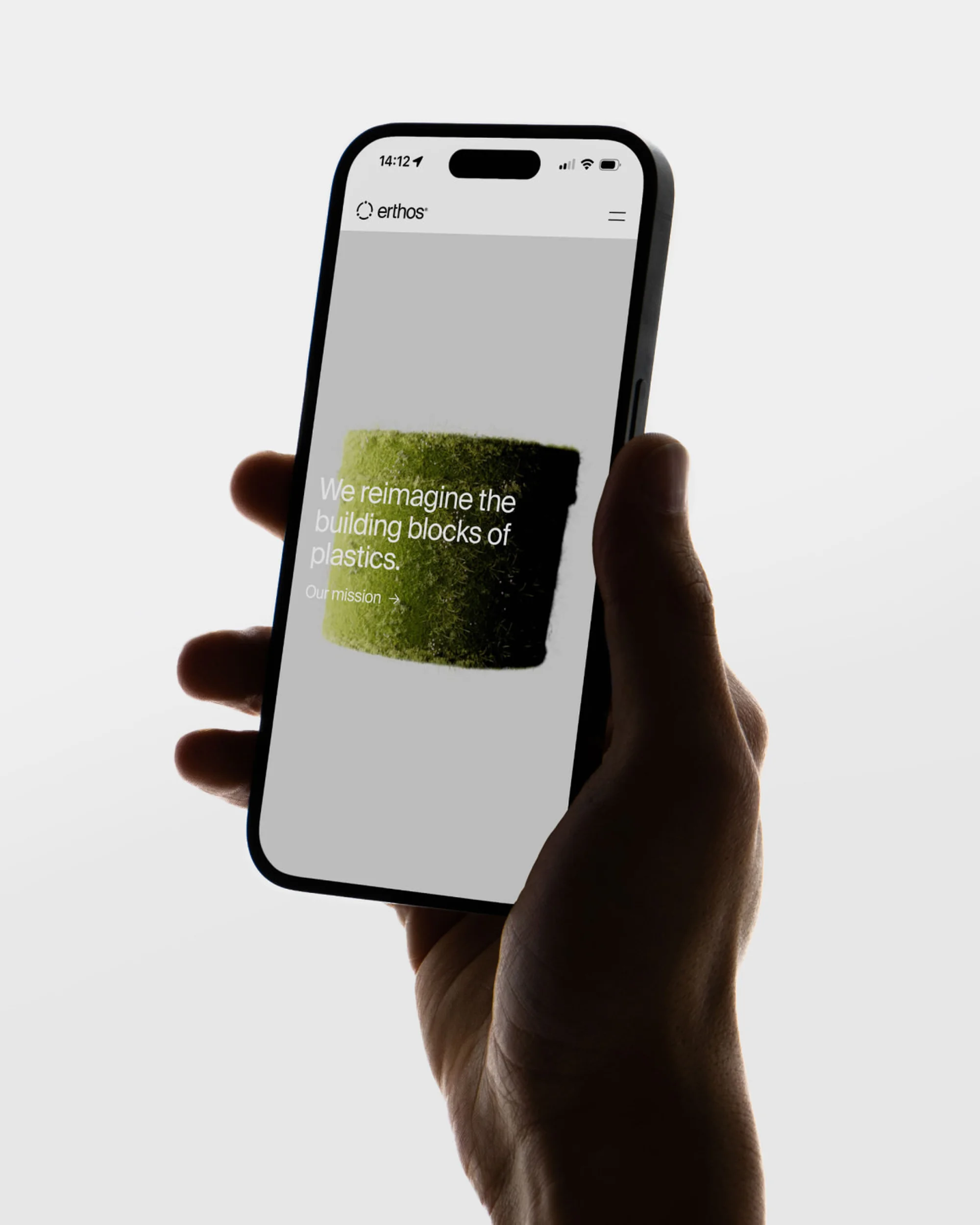 Hand holding smartphone displaying the ethos.com website, featuring text and a green block on a light grey background.