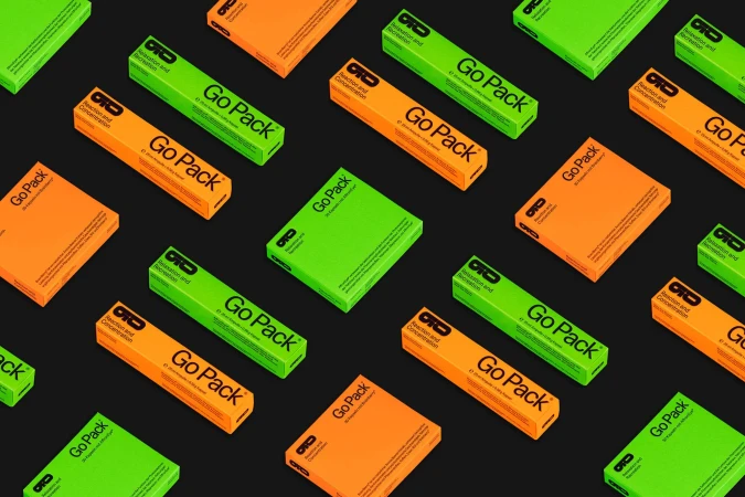 Isometric product shot: multiple bright green and orange Go Pack boxes arranged on a dark background, showcasing vibrant packaging design.