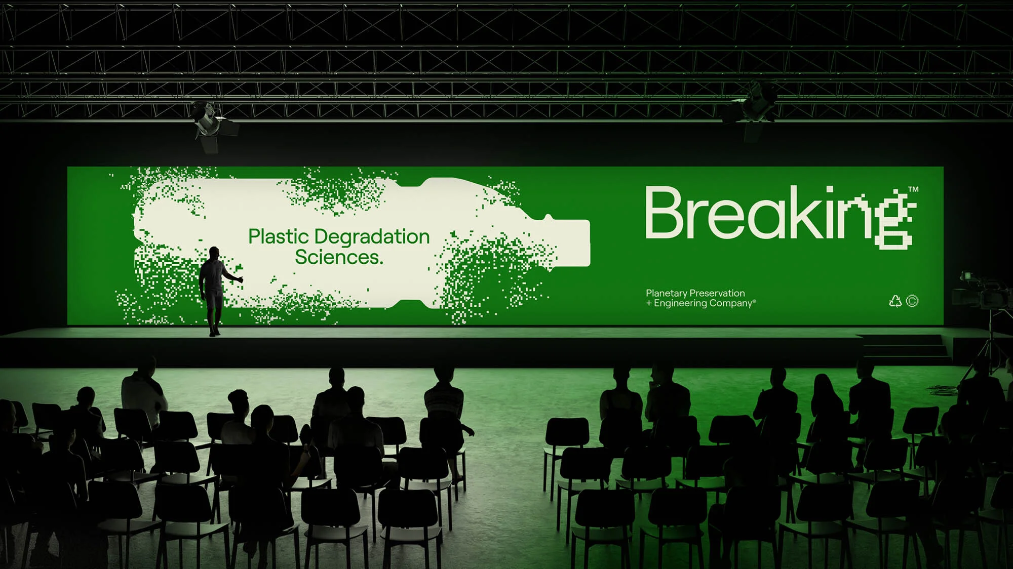 A person is presenting on stage in front of an audience with a presentation about plastic degradation and planetary preservation.