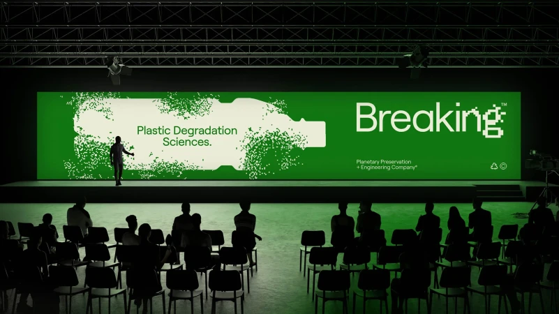 A person is presenting on stage in front of an audience with a presentation about plastic degradation and planetary preservation.