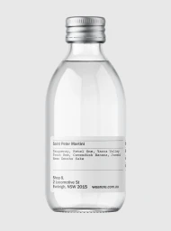 Clear glass bottle with a silver cap and a white label featuring black typography against a light grey background.