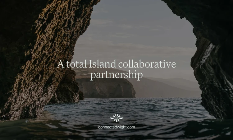 Coastal view through a dark rocky archway, featuring blue ocean water, distant cliffs, and sky with an island collaboration message.