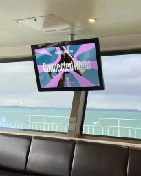 Connected Wight brand identity displayed on a mounted screen inside a ferry cabin overlooking the ocean.