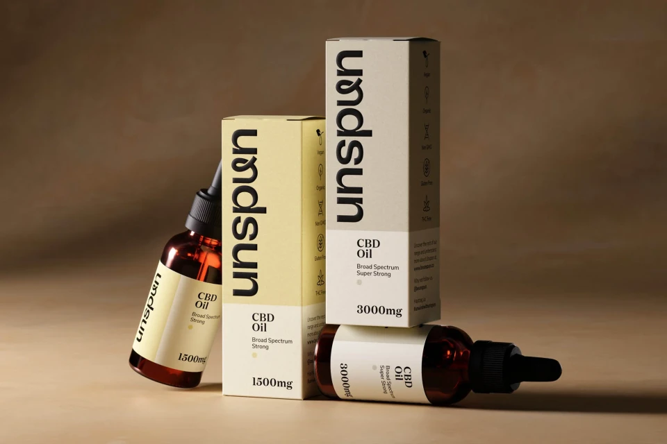 Close-up of Unspun CBD oil bottles and packaging in tan and amber tones, emphasizing product details and minimalistic design.