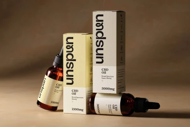 Amber glass dropper bottles and cream packaging boxes with black typography on a warm beige background.
