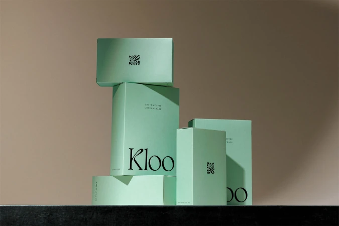 Stacked light green boxes of Kloo Craft Coffee Concentrate against a neutral backdrop, emphasizing product presentation and minimalist design.