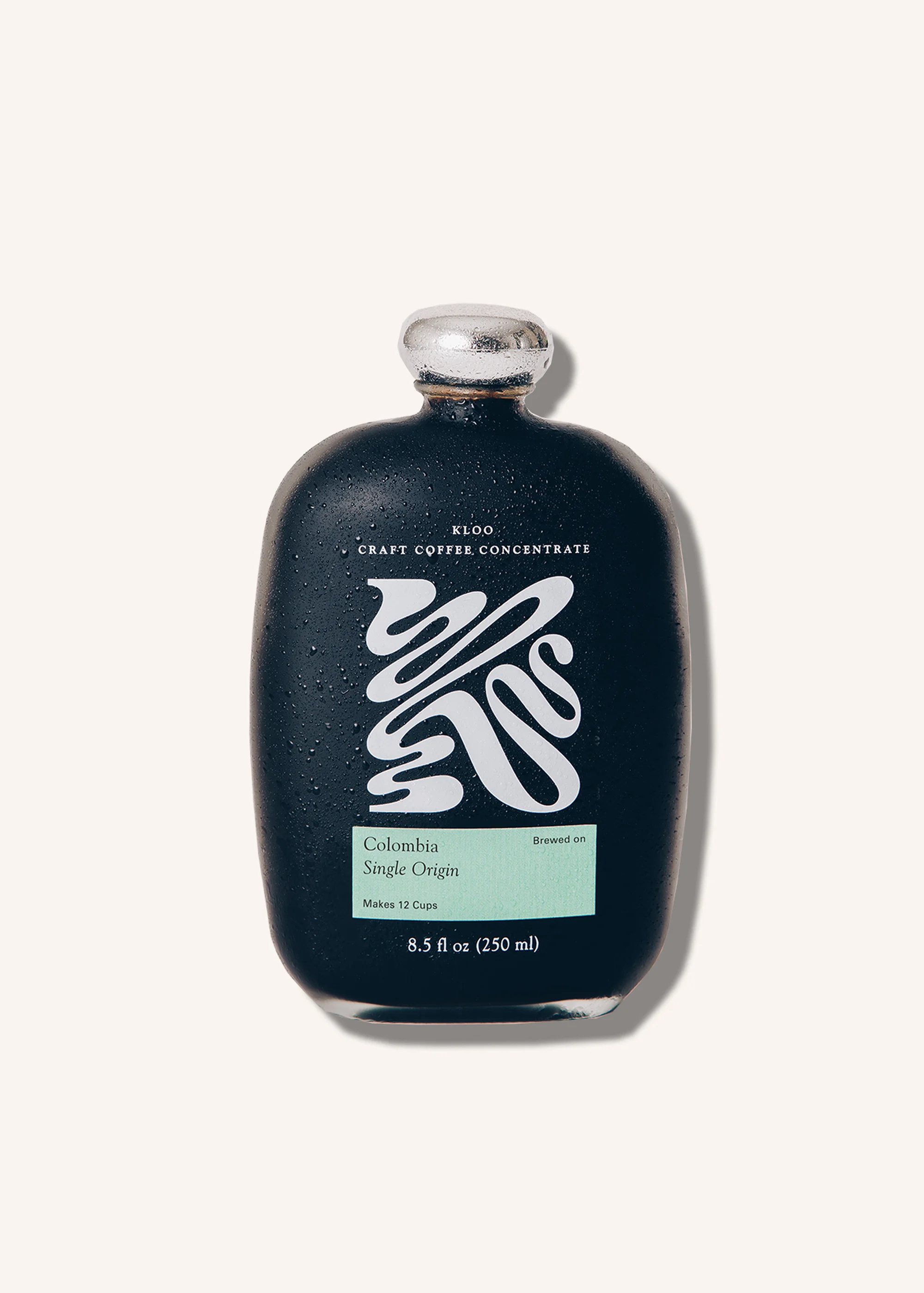 Dark bottle of ELDO craft coffee concentrate with a white logo and label, set against a solid off-white background in a studio product shot.