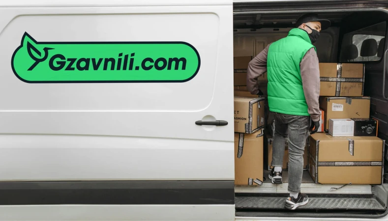 Delivery worker loading boxes into van with company logo 'Gzavnili.com' on the side.  Parcel delivery service in urban setting.