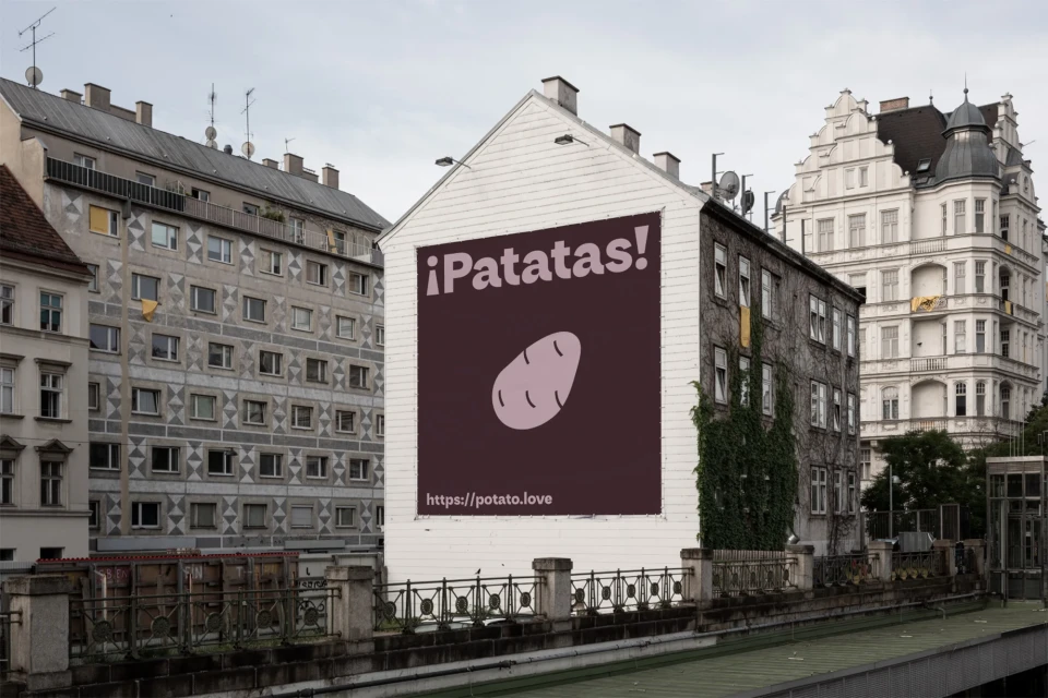 Building exterior with a large advertisement featuring a potato graphic and the text ¡Patatas! and the URL https://potato.love.